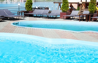 Photo of Swimming pools with clean blue water and lounge chairs outdoors