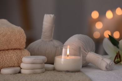 Spa composition with burning candle and herbal bags on massage table in wellness center