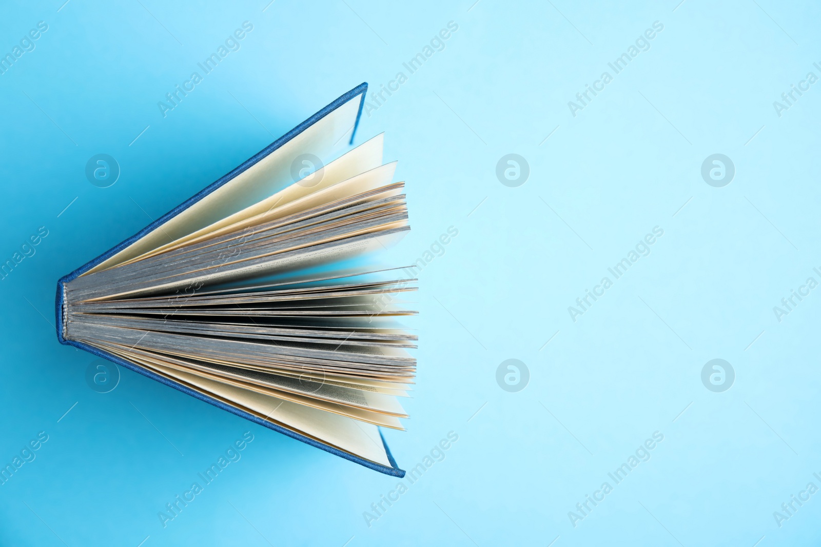 Photo of Hardcover book on light blue background, top view. Space for text