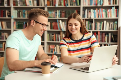 Young people discussing group project at table in library