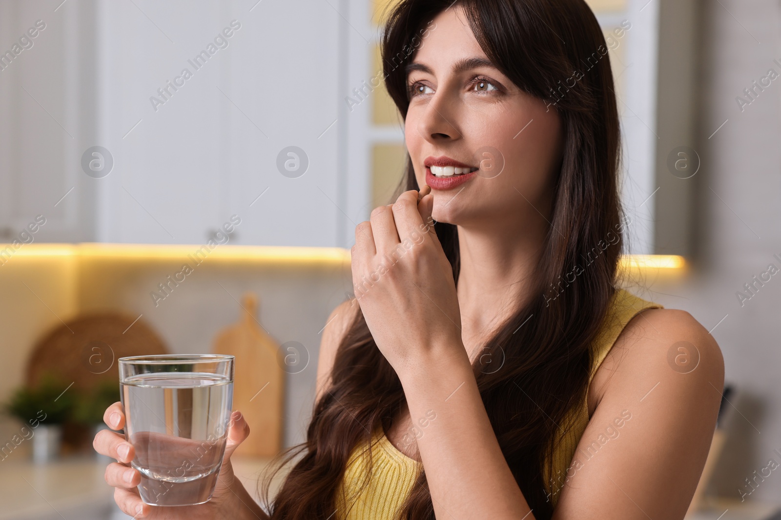 Photo of Beautiful woman taking vitamin pill at home