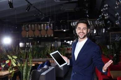 Photo of Young business owner with tablet in his cafe. Space for text
