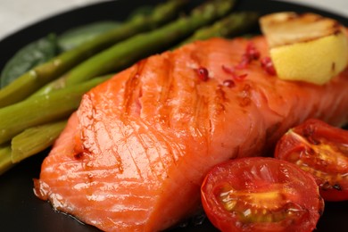 Photo of Tasty grilled salmon with tomatoes, lemon and asparagus, closeup