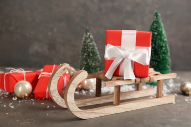 Photo of Beautiful Christmas composition with miniature sleigh on grey table