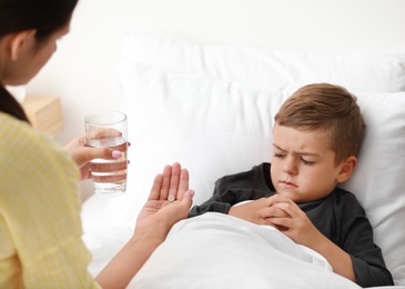 Photo of Mother giving medicine to her sick son in bed