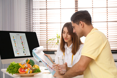 Photo of Young nutritionist consulting patient at table in clinic