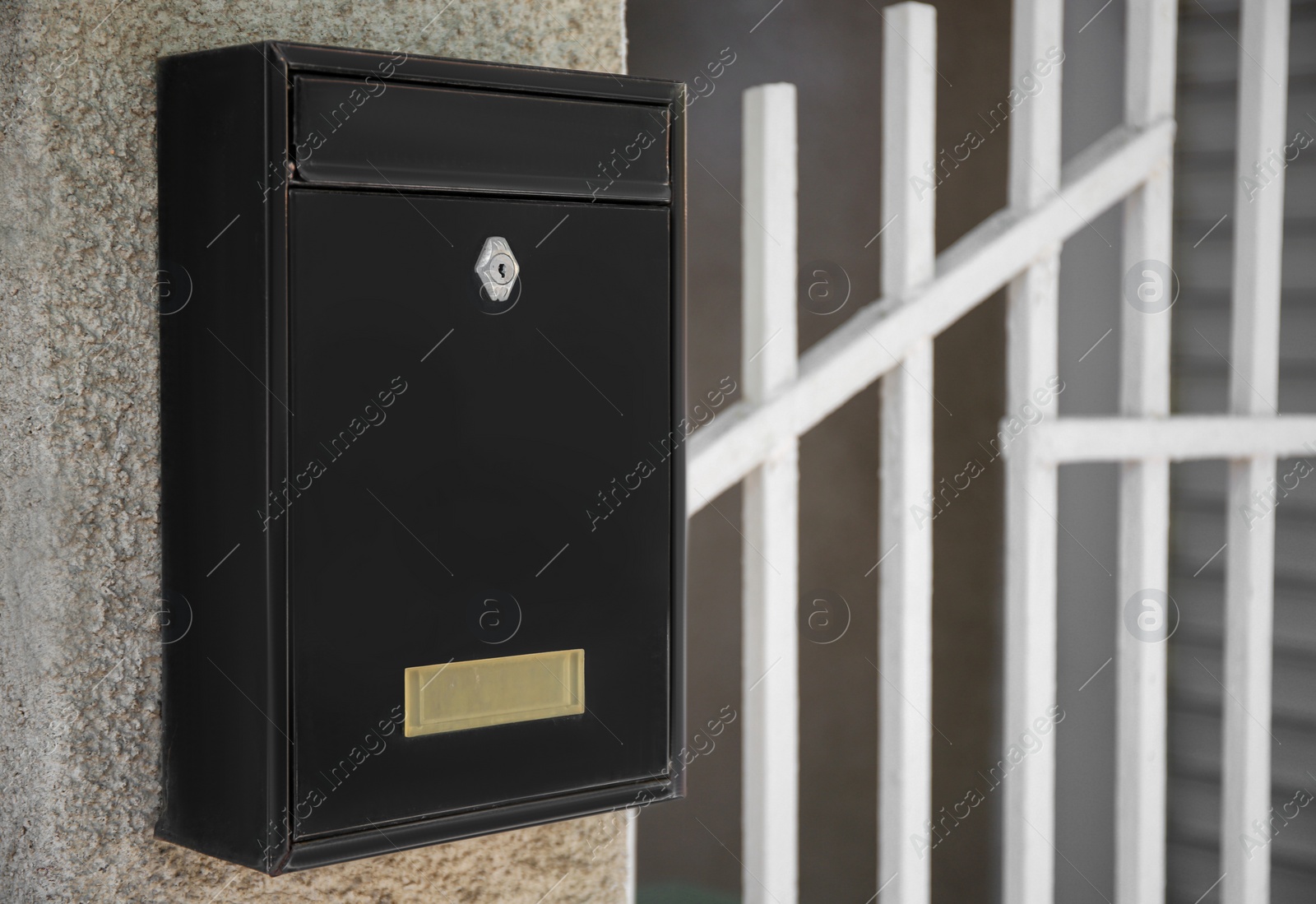 Photo of Black metal letter box on beige textured wall, closeup and space for text