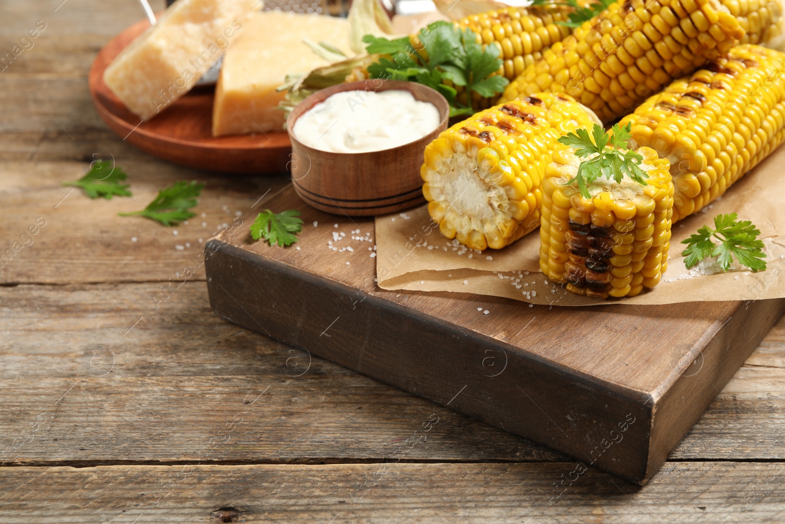 Photo of Delicious grilled corn cobs on wooden table. Space for text