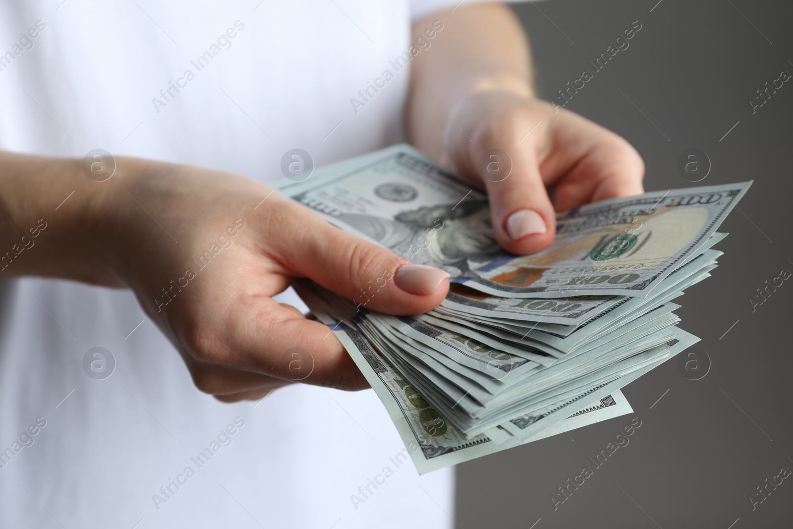 Photo of Money exchange. Woman counting dollar banknotes on grey background, closeup