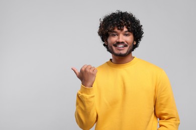 Handsome smiling man on light grey background, space for text