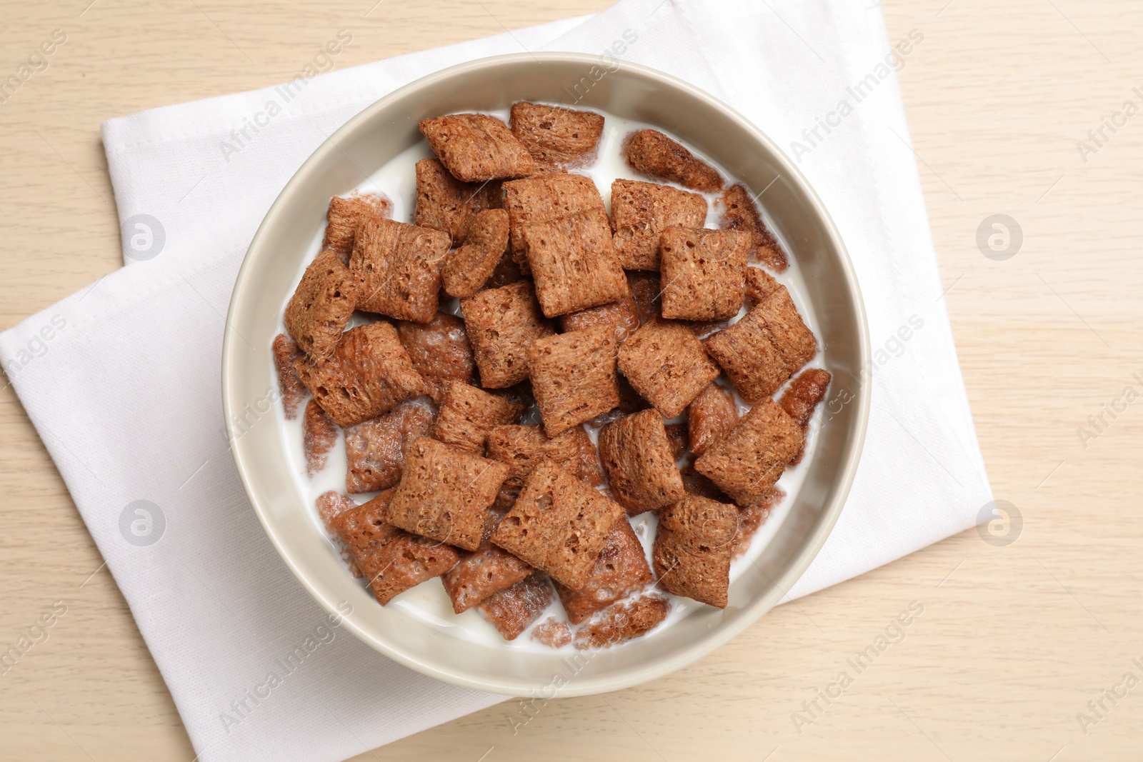 Photo of Bowl with tasty corn pads and milk on wooden table, flat lay