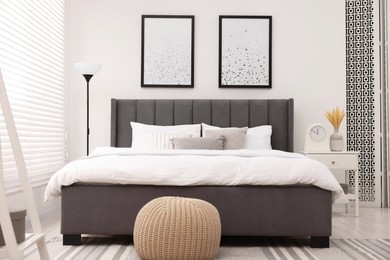 Stylish bedroom interior with large bed, bedside table and lamp