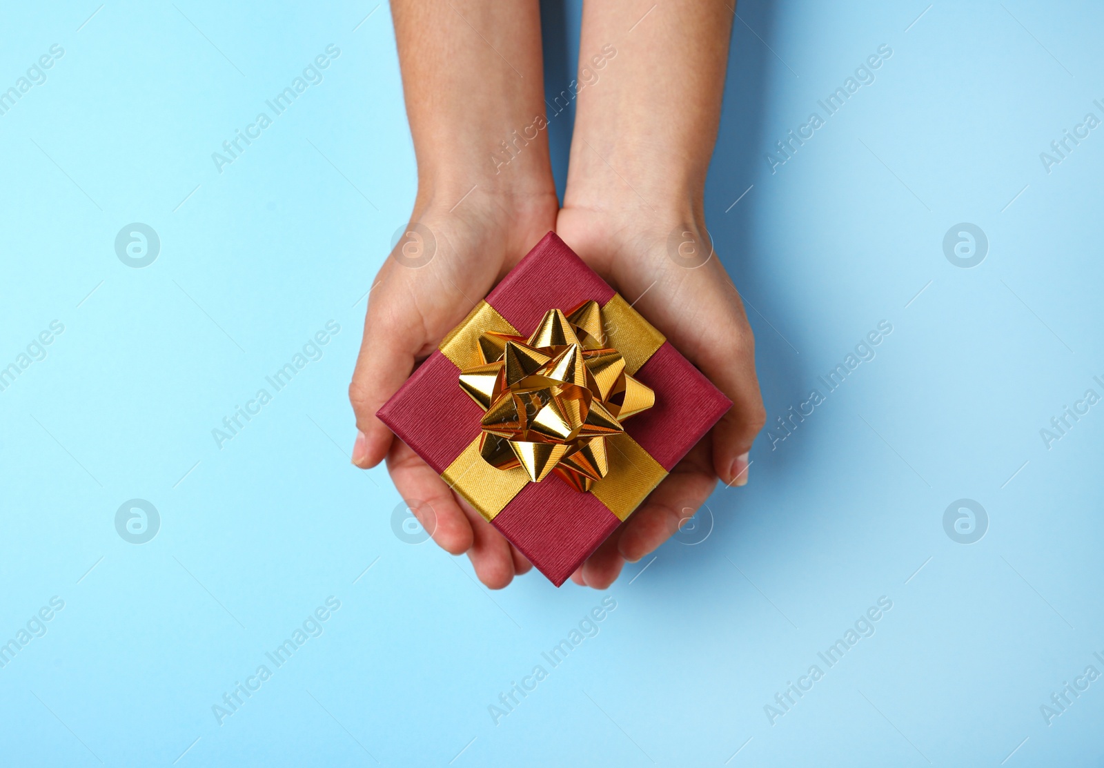 Photo of Woman holding beautiful gift box on blue background, top view