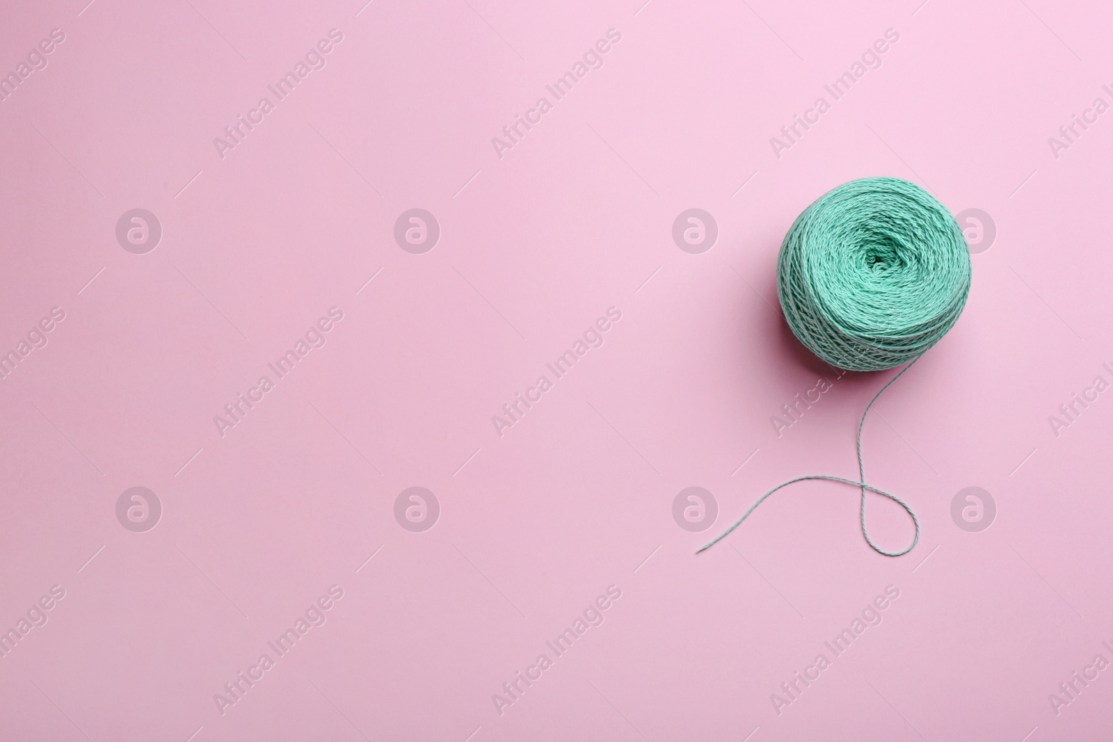 Photo of Clew of knitting threads on color background, top view with space for text. Sewing stuff