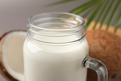 Photo of Mason jar of delicious coconut milk on grey background, closeup