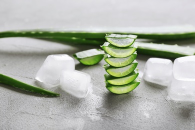 Photo of Slices of aloe vera and ice cubes on gray table