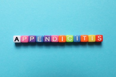 Photo of Word Appendicitis made of color cubes with letters on light blue background, top view