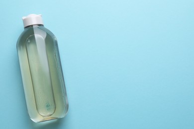 Photo of Micellar water on light blue background, top view. Space for text