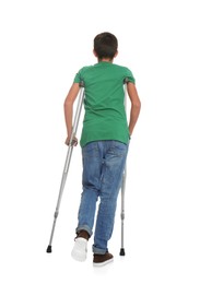 Photo of Teenage boy with injured leg using crutches on white background, back view