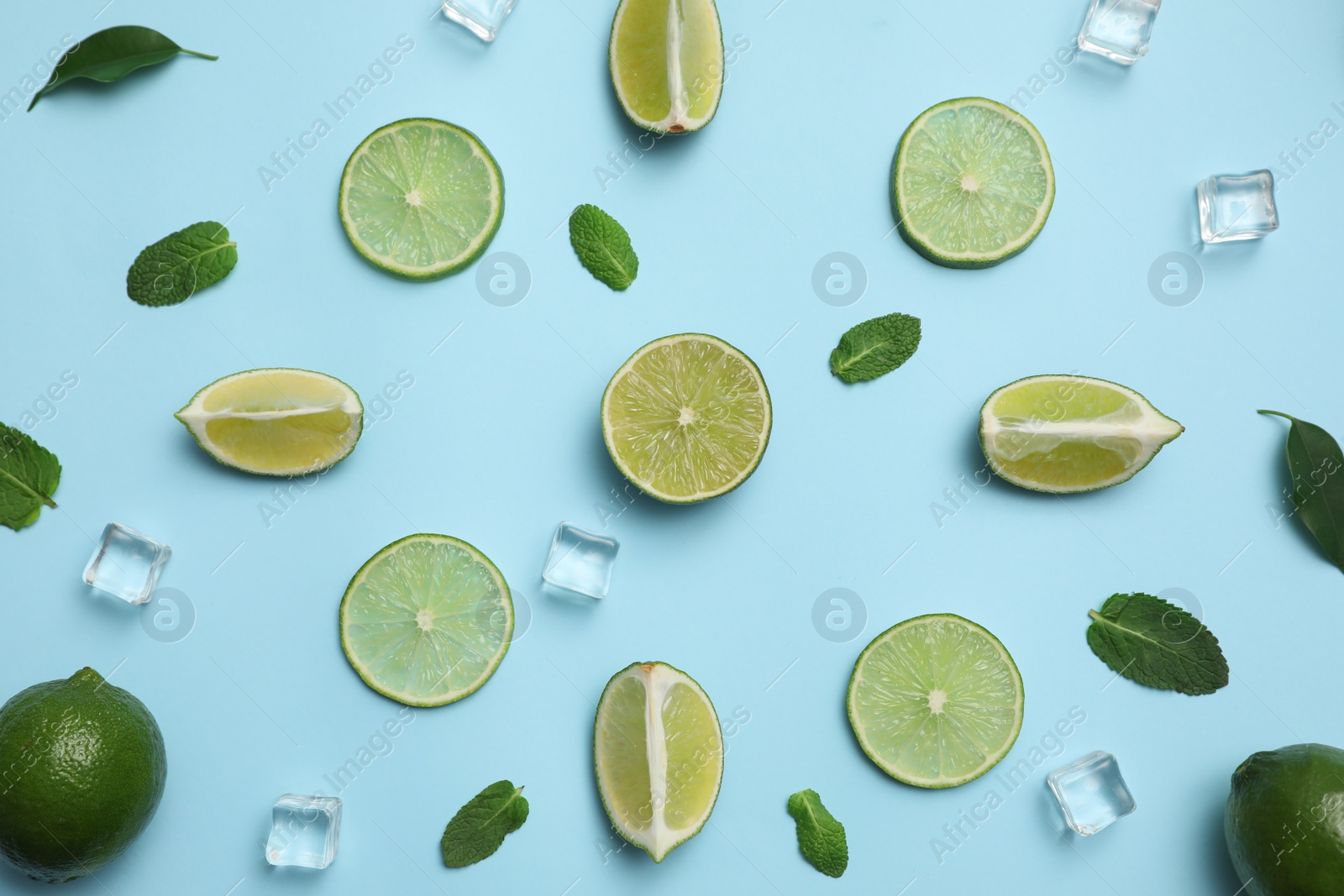 Photo of Flat lay composition with fresh juicy limes, mint and ice cubes on light blue background