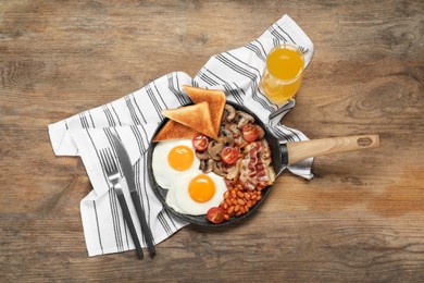 Photo of Serving pan with fried eggs, mushrooms, beans, bacon, tomatoes and toasted bread on wooden table, flat lay. Traditional English breakfast