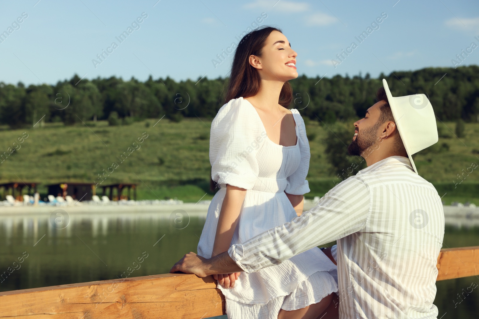 Photo of Romantic date. Beautiful couple spending time together near lake, space for text