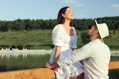 Photo of Romantic date. Beautiful couple spending time together near lake, space for text