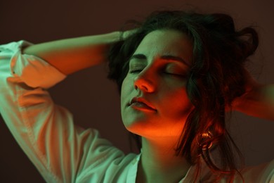 Portrait of beautiful young woman on color background with neon lights, closeup