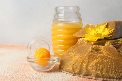 Natural beeswax blocks, flower and jar of honey on color textured table, closeup. Space for text