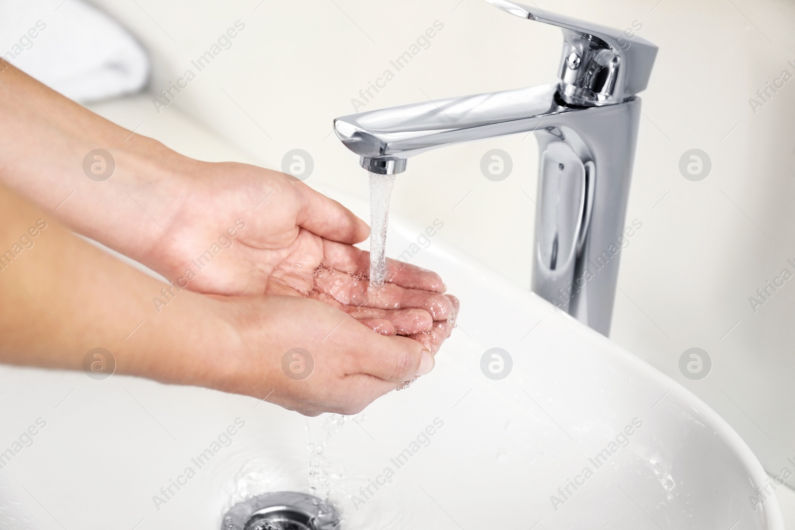 Photo of Young woman washing hands over sink in bathroom, closeup