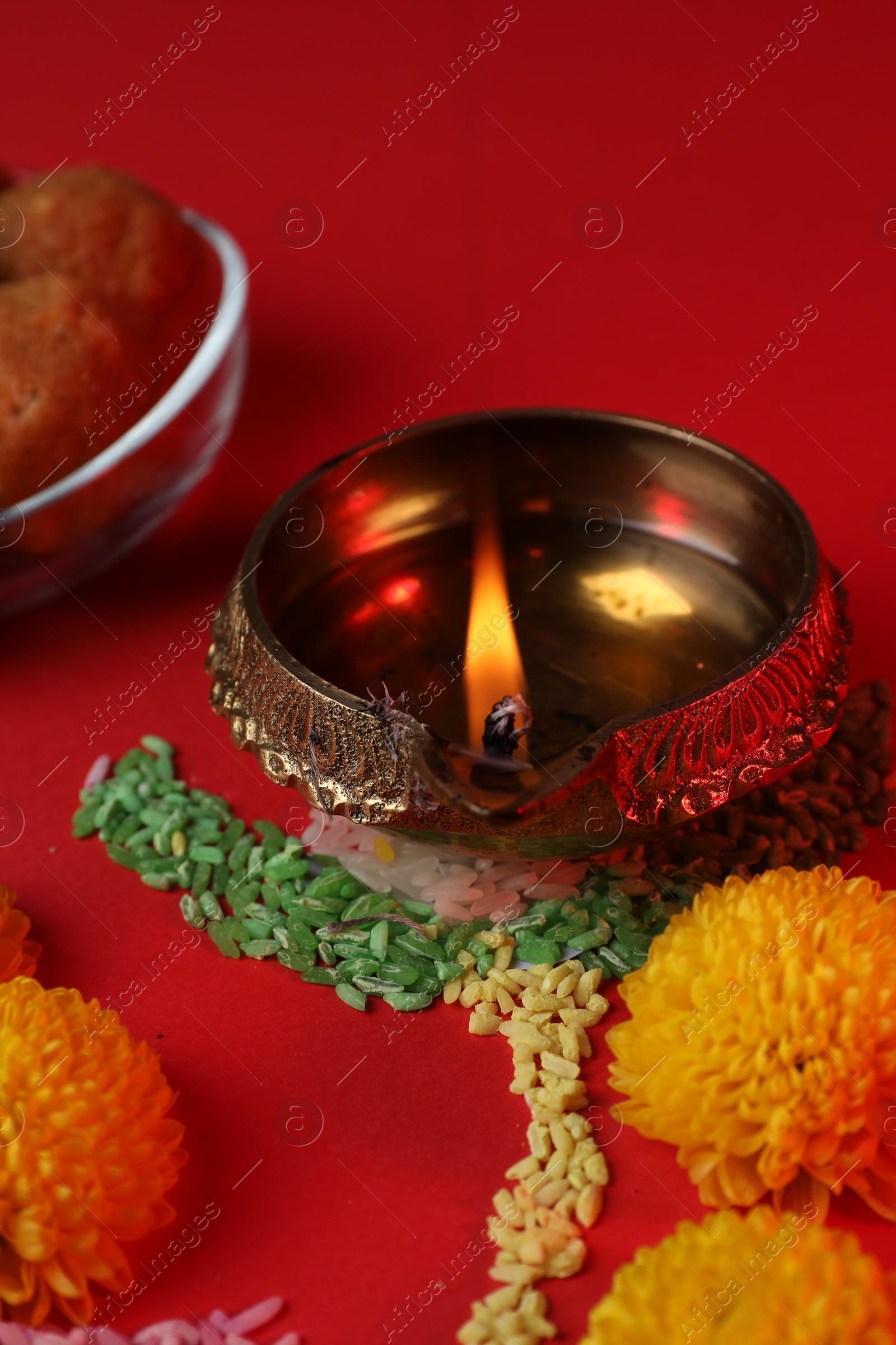 Photo of Happy Diwali. Diya lamp, colorful rangoli and flowers on red table, closeup