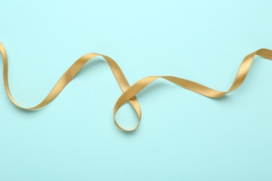 Photo of Beautiful golden ribbon on light blue background, top view