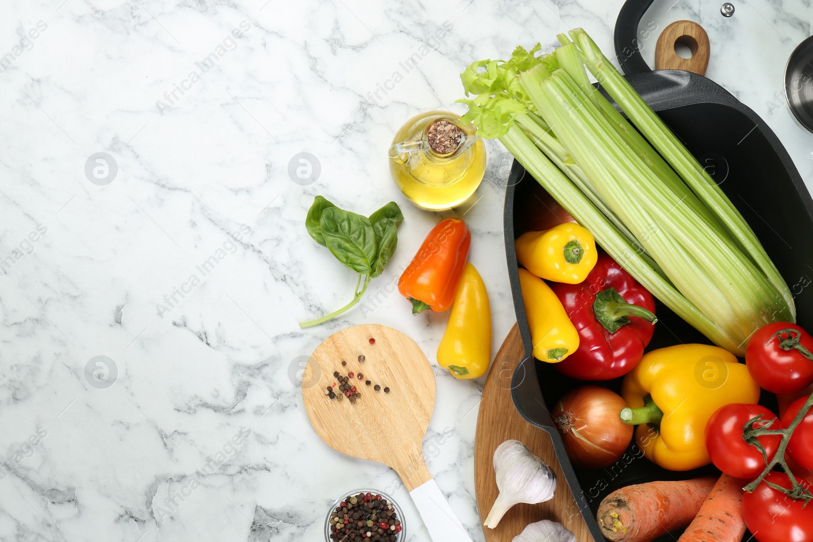 Photo of Black pot with round spatula and different products on white marble table, flat lay. Space for text