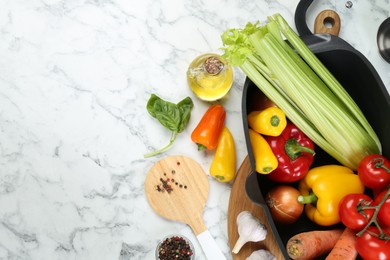 Photo of Black pot with round spatula and different products on white marble table, flat lay. Space for text