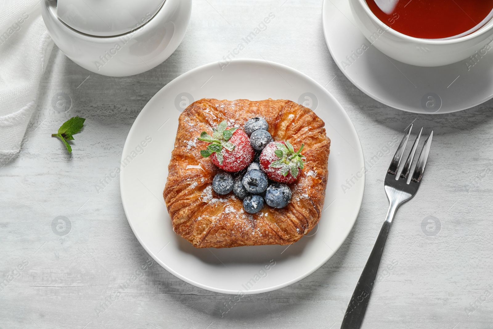 Photo of Fresh delicious puff pastry with sweet berries served on light table, flat lay