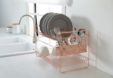 Photo of Clean dishes on drying rack in modern kitchen interior