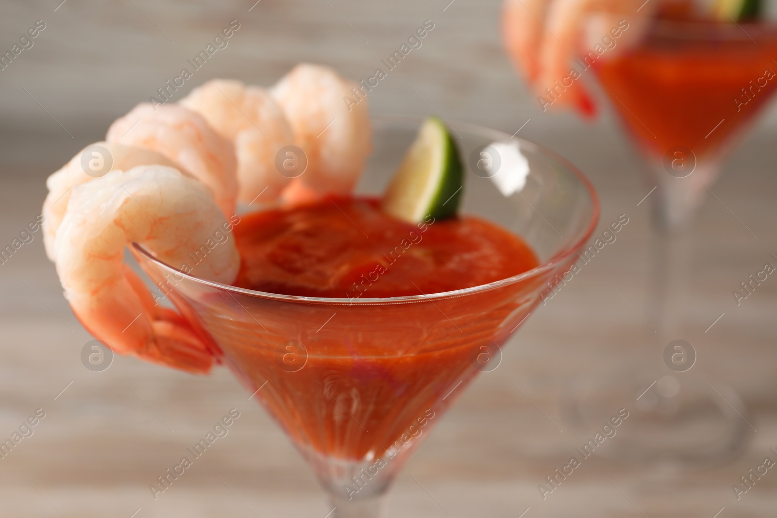 Photo of Tasty shrimp cocktail with sauce in glass on table, closeup