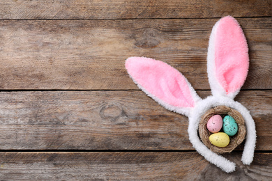 Photo of Headband with bunny ears, painted eggs and space for text on wooden background, flat lay. Easter holiday