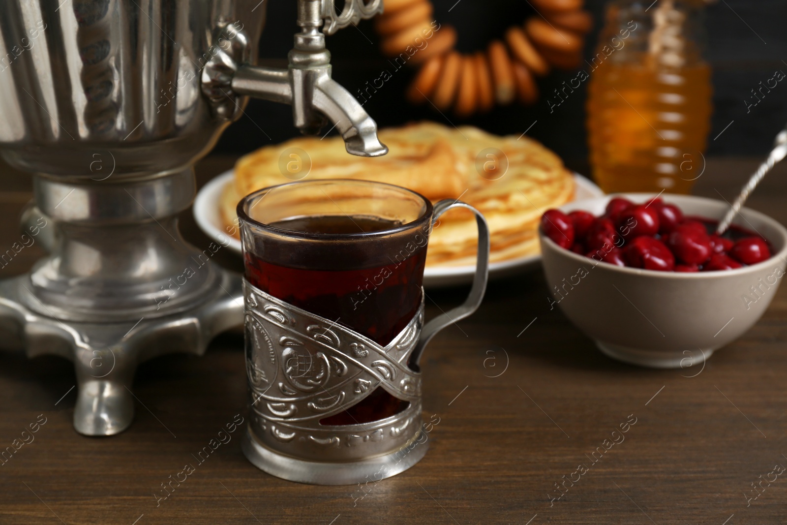 Photo of Metal samovar with cup of tea and treats on wooden table