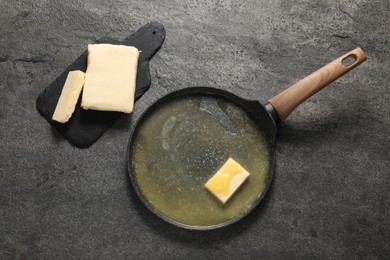 Photo of Melting butter in frying pan and dairy product on grey table, top view