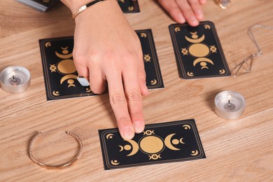 Photo of Soothsayer predicting future with tarot cards at wooden table, closeup