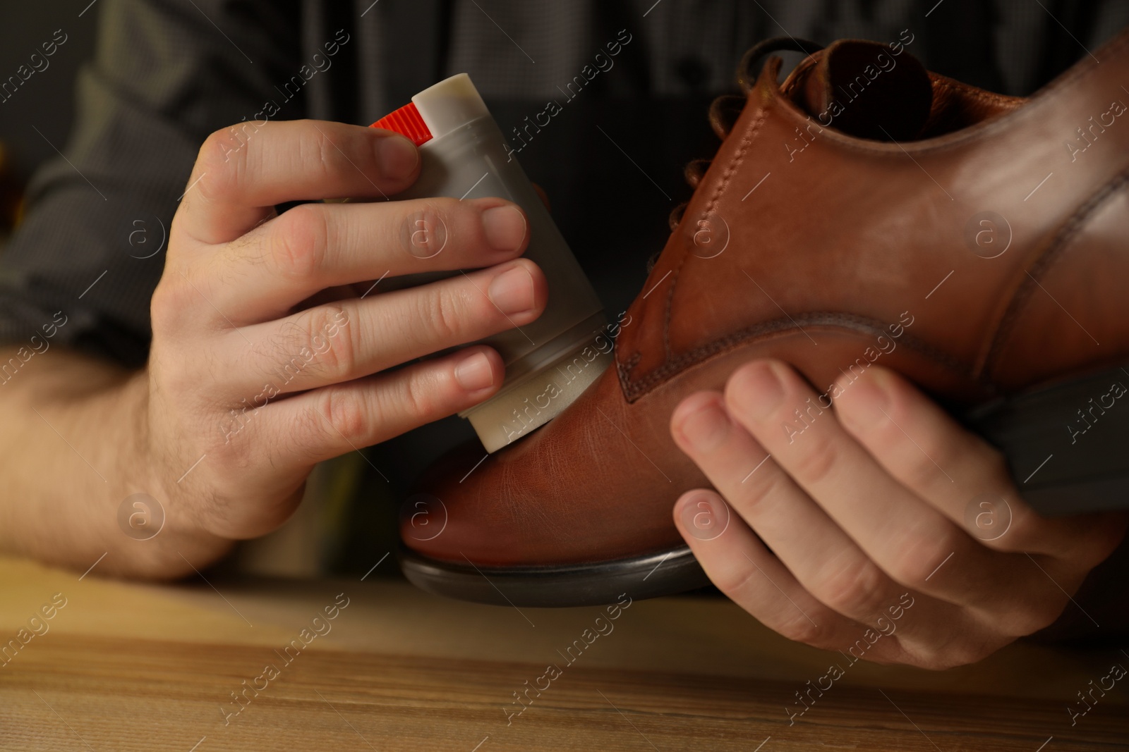 Photo of Craftsman taking professional care of brown leather shoe in workshop, closeup