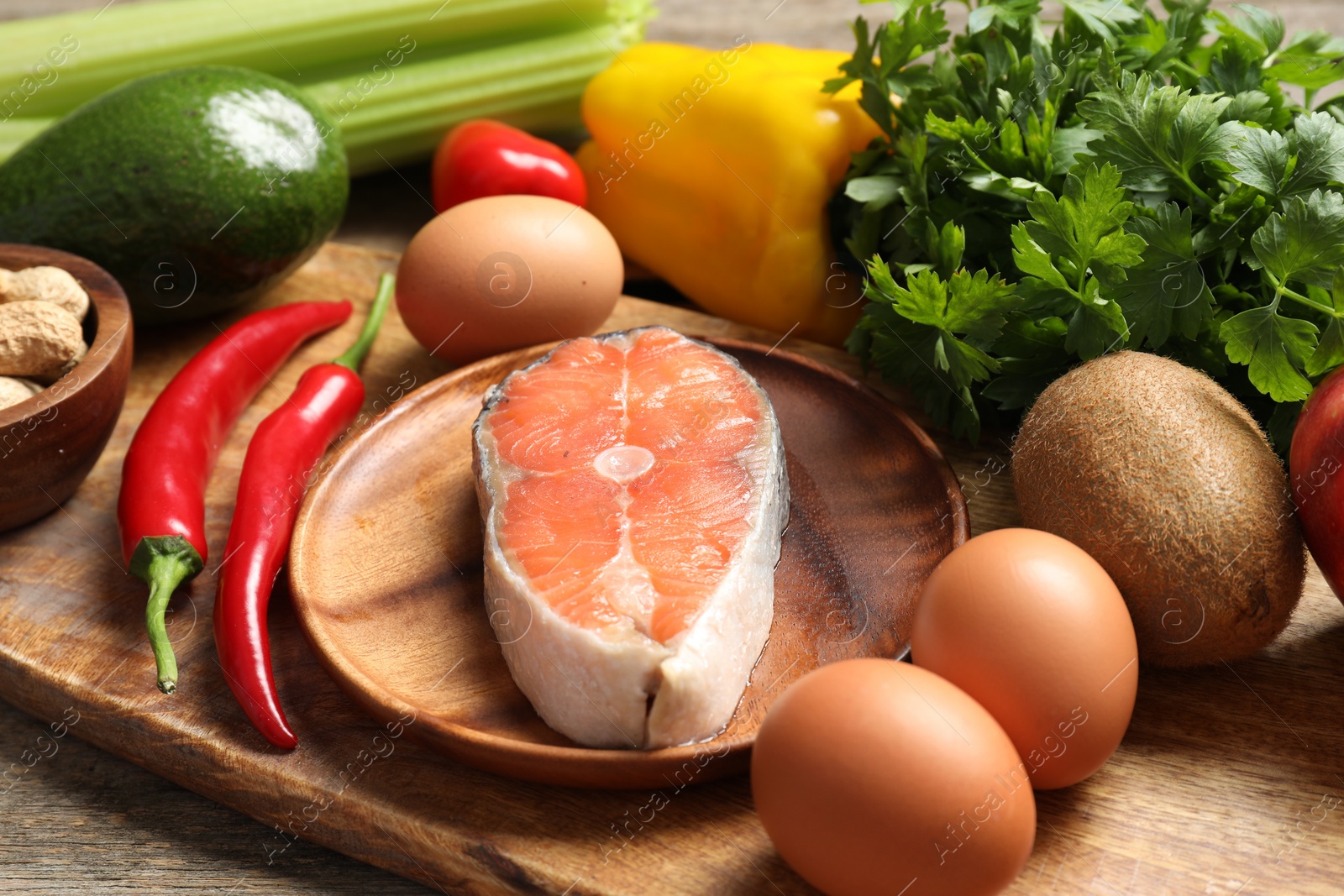 Photo of Healthy meal. Different vegetables and raw salmon on wooden table