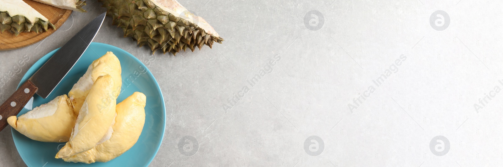 Image of Plate with fresh ripe durian and knife on grey table, flat lay with space for text. Banner design