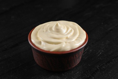 Photo of Fresh mayonnaise sauce in bowl on black table, closeup