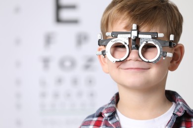 Photo of Little boy with trial frame against vision test chart