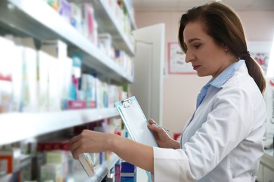 Photo of Professional pharmacist near shelves with merchandise in modern drugstore