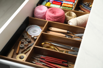 Photo of Sewing accessories in open desk drawer indoors, closeup