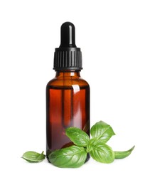 Photo of Glass bottle of basil essential oil and leaves on white background