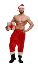 Attractive young man with muscular body in Santa hat holding Christmas gift box on white background